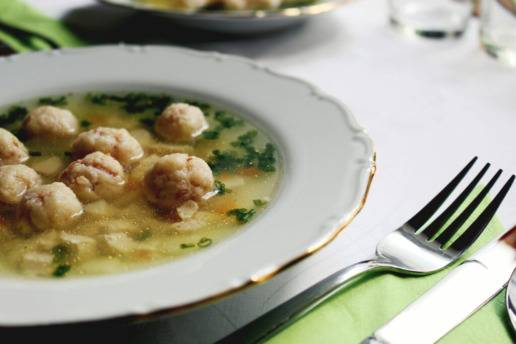 Italian Wedding Soup with Mushroom "Meatballs". A close-up of a flavorful Italian wedding soup garnished with herbs, served in an elegant setting.