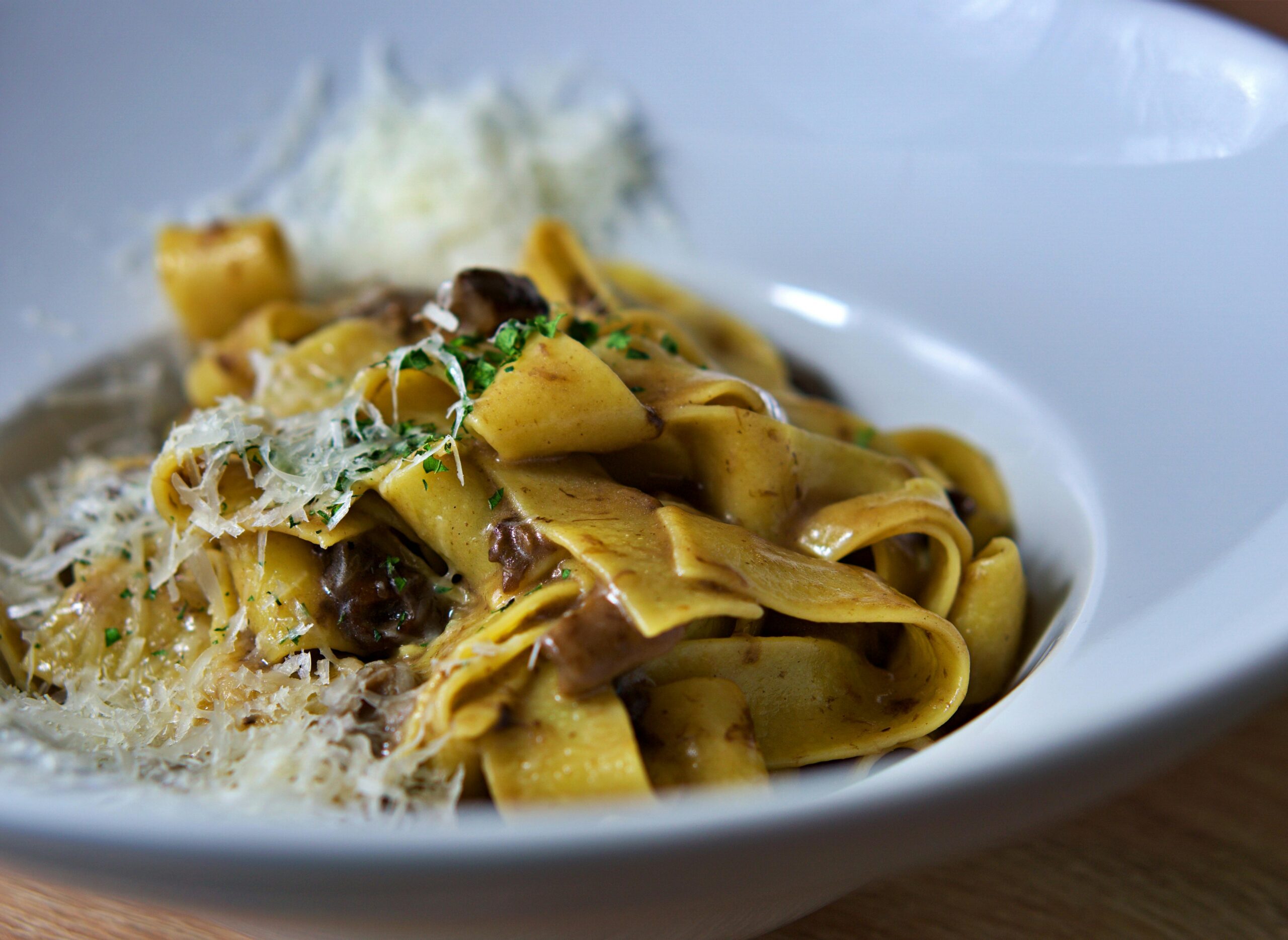 Italian Oyster Mushroom Garlic Butter Pasta: Close-up of pappardelle pasta topped with parmesan cheese and mushrooms, perfect for Italian cuisine lovers.