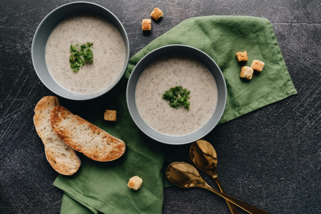 Creamy Lions Mane Chowder - A still life of creamy soup in bowls with parsley garnish, served with bread and croutons.
