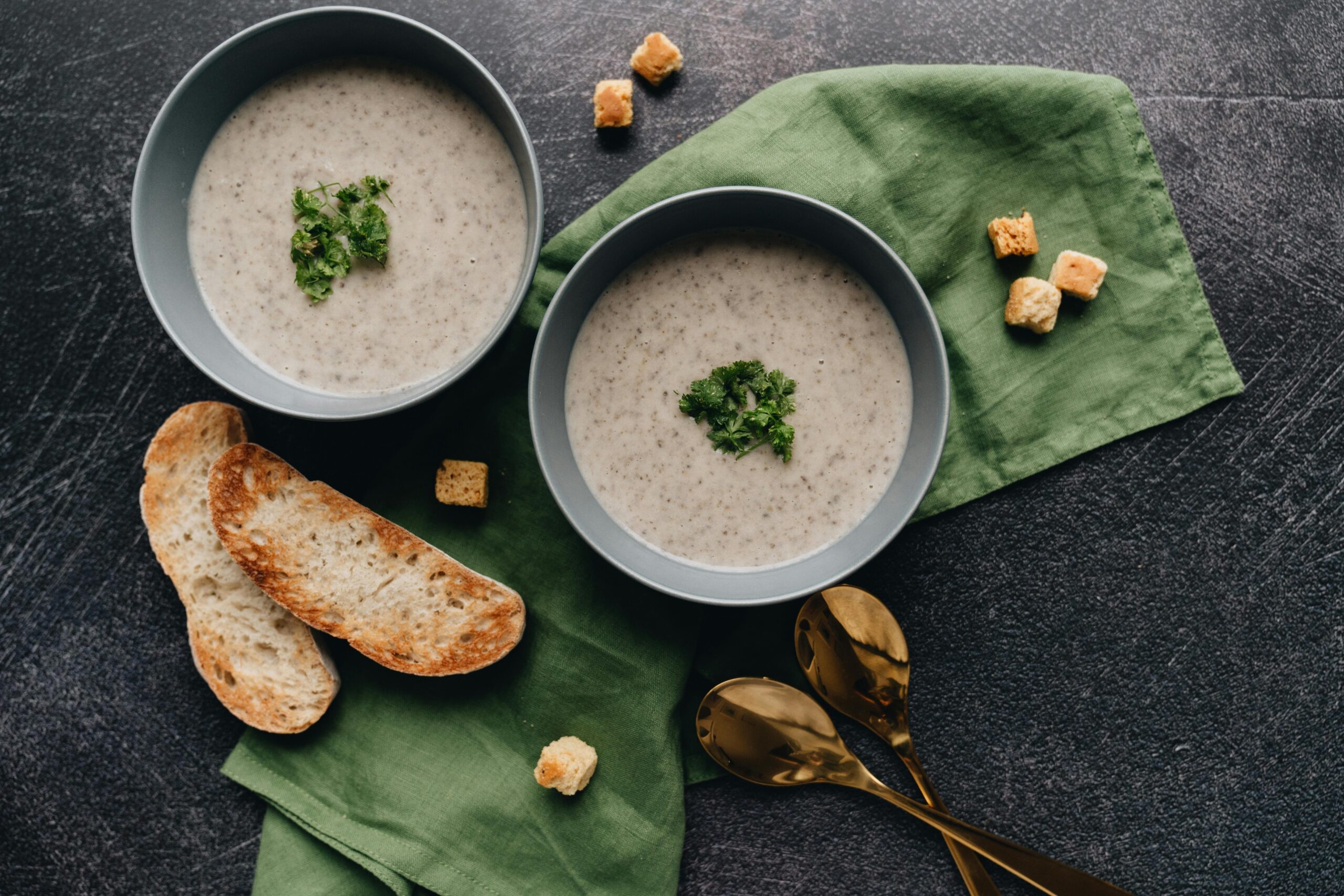 Creamy Lions Mane Chowder - A still life of creamy soup in bowls with parsley garnish, served with bread and croutons.